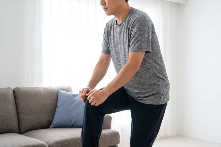 A man doing a standing knee-lift exercise at home
